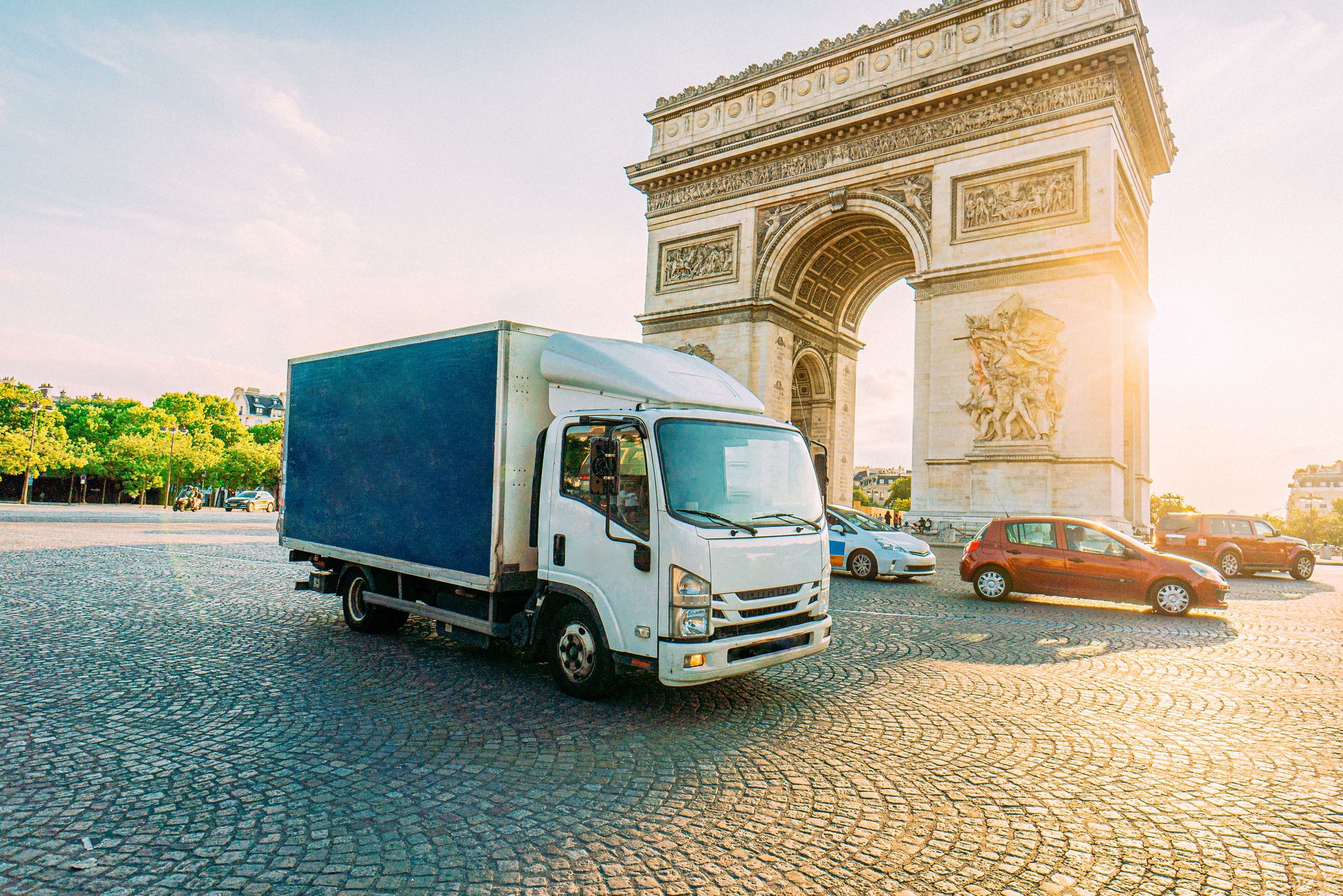 Cabover Style Box Truck Driving on the Pl. Charles de Gaulle Traffic Circle around Arc De Triomphe in Downtown Paris on a Sunny Day